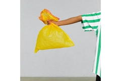 Boy holding a yellow trash bag.